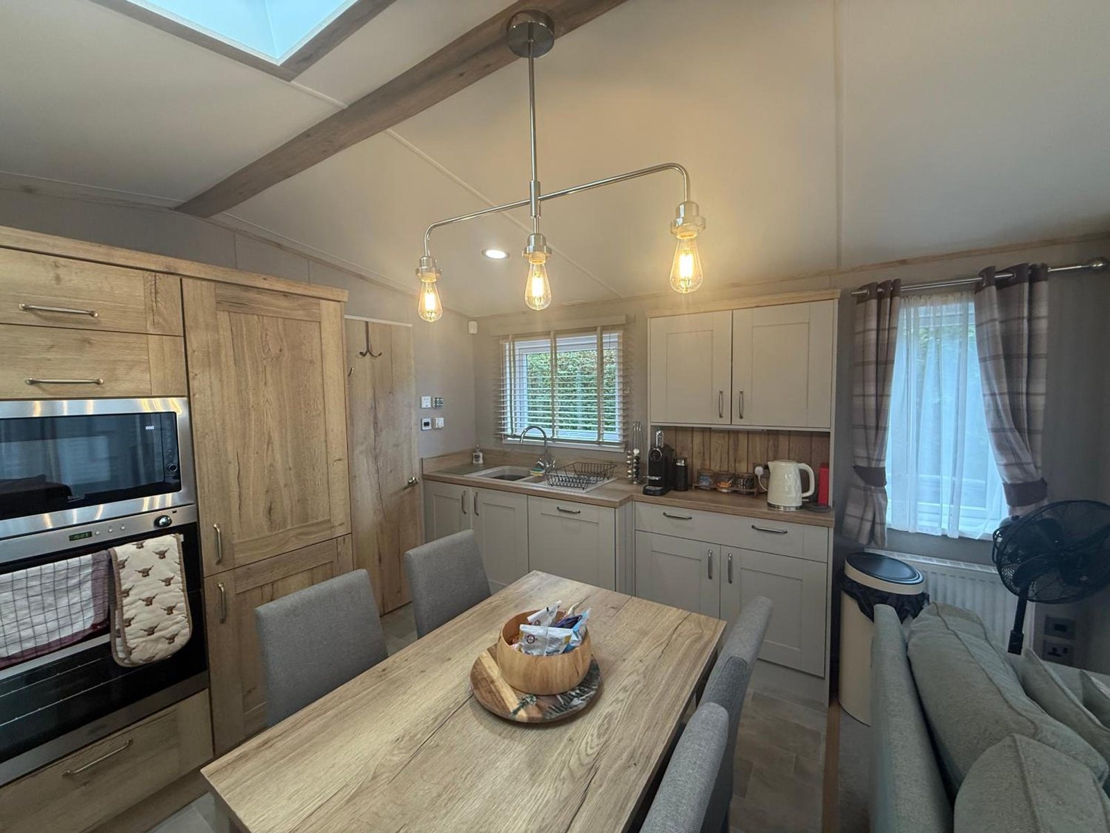 Oak kitchen units and a dining table under three bulb pendants