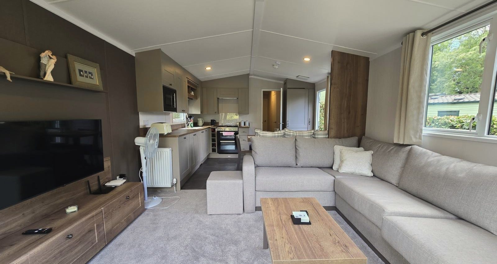 An open-plan living room with a large corner sofa, looking through to the kitchen