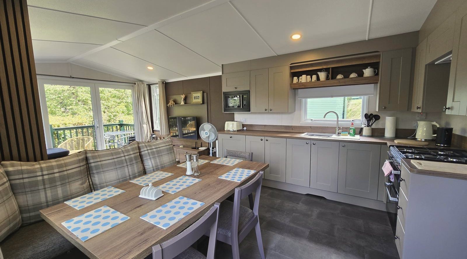 A kitchen and dining area with bench seating around a table, the kitchen units along the far wall