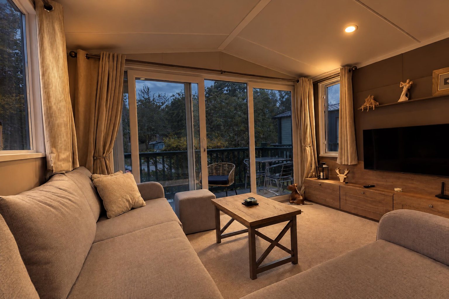 The same living room in the evening, downlights on and blue dusk through the glass doors